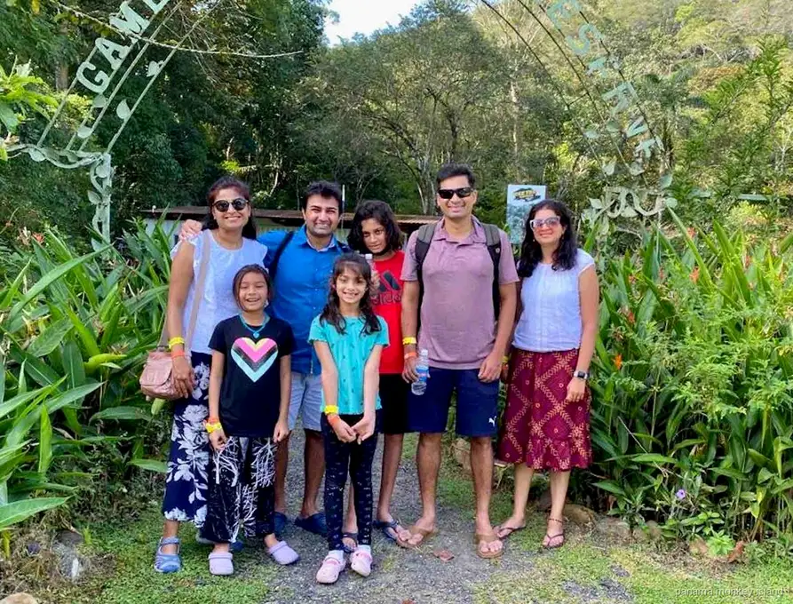 Familia posando bajo el arco verde de entrada de una reserva selvática en el tour combinado panama monkey island