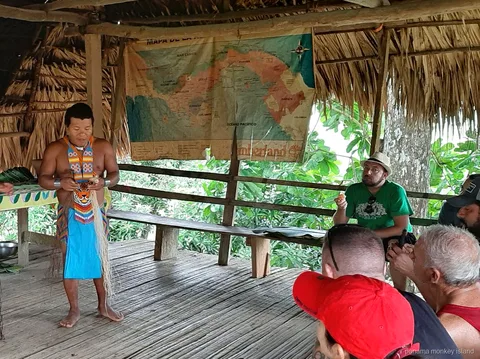 Guía Emberá con vestimenta tradicional hablando a los visitantes bajo un techo de paja en un tour a la isla de los monos Panamá
