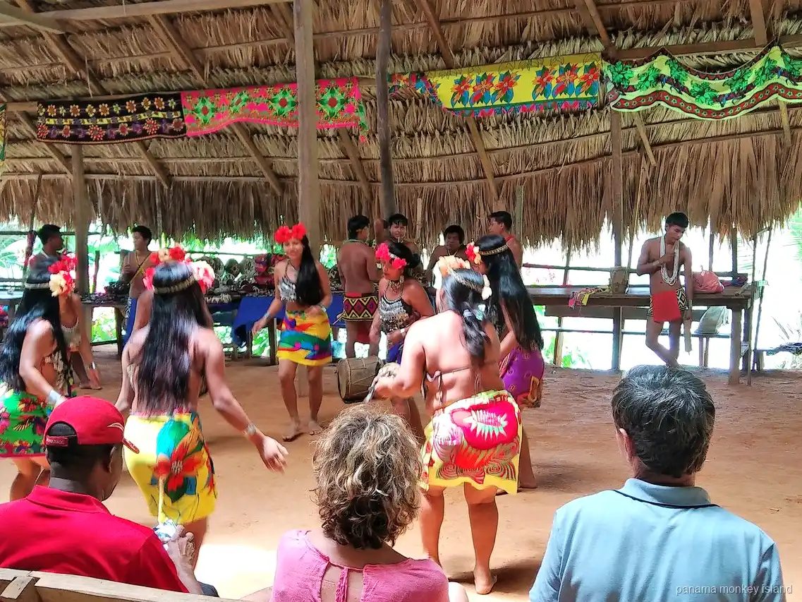 Bailarines Emberá con faldas coloridas actuando para los visitantes en una choza, tour a la isla de los monos Panamá
