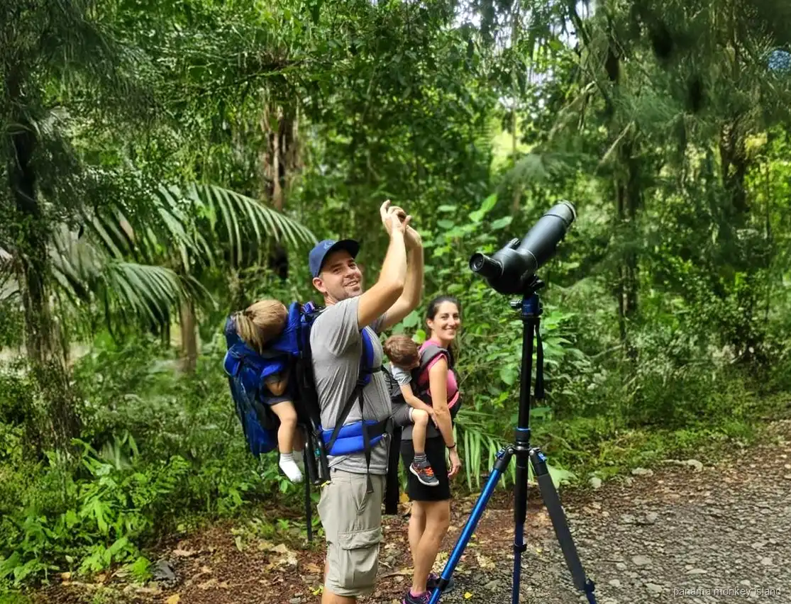 Family with a spotting scope on a rainforest trail looking for wildlife, panama monkey island jungle tour