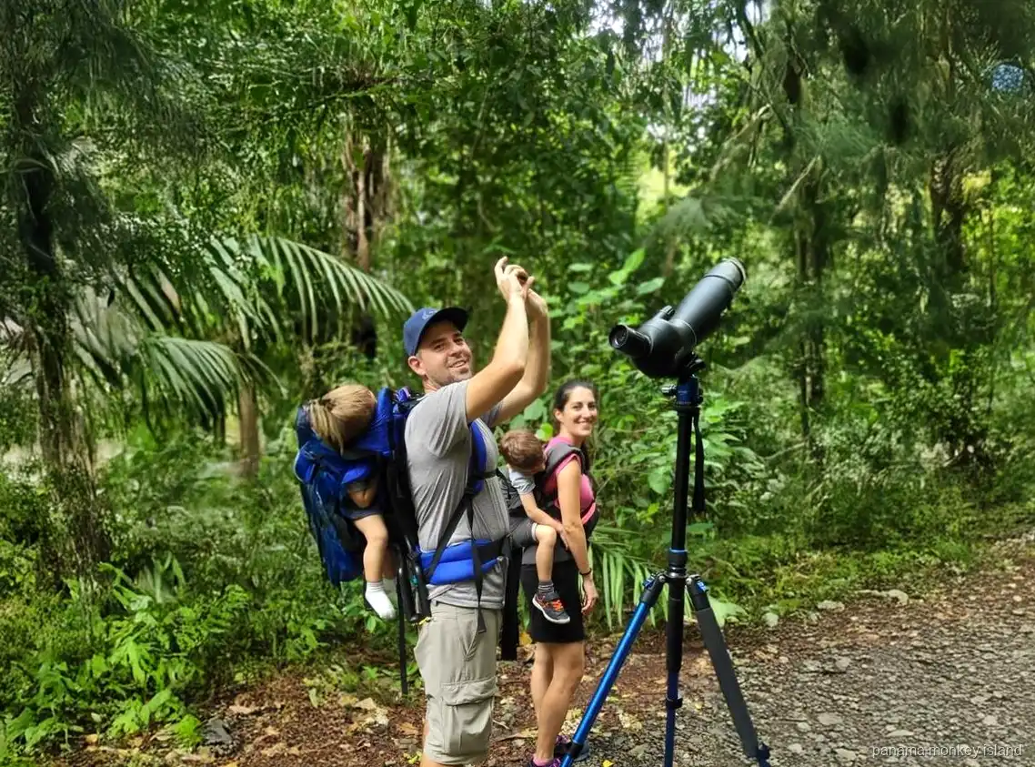 Familia con un telescopio de observación en un sendero del bosque buscando fauna, tour de selva isla de los monos Panamá